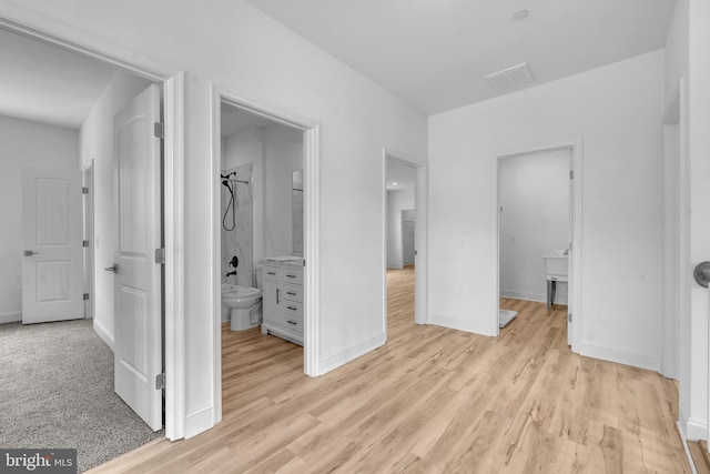 unfurnished bedroom with light wood-style floors, ensuite bath, and baseboards