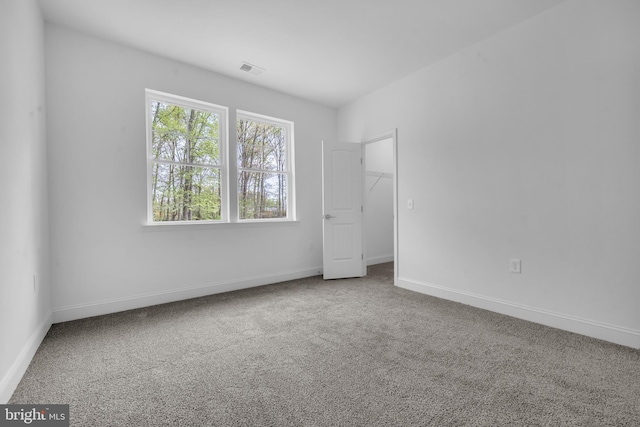 unfurnished bedroom with baseboards, a spacious closet, and carpet flooring