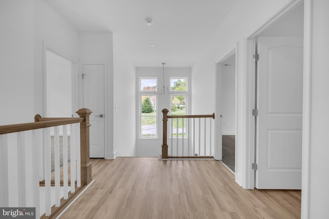 hallway featuring an upstairs landing and light wood-style flooring