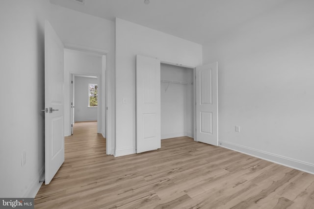 unfurnished bedroom with light wood-type flooring, a closet, and baseboards
