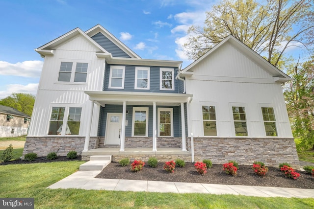 view of front of property featuring a front lawn, stone siding, board and batten siding, and covered porch