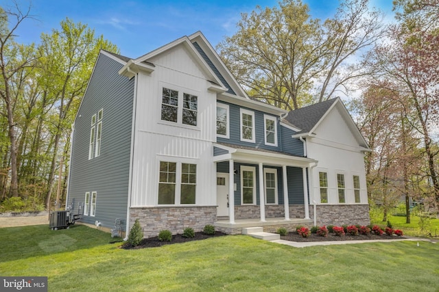 view of front of house featuring cooling unit, a front yard, stone siding, and covered porch