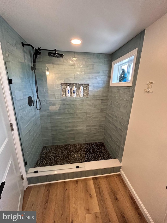 bathroom featuring a tile shower and hardwood / wood-style floors