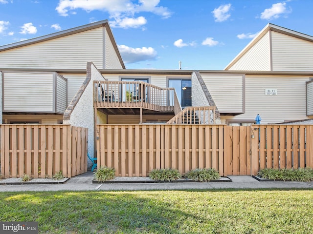 back of property with a lawn and a wooden deck