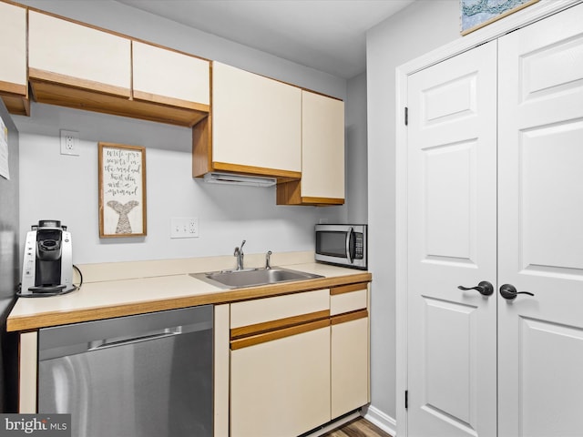 kitchen with wood-type flooring, white cabinets, appliances with stainless steel finishes, and sink