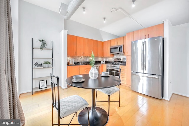 kitchen featuring decorative backsplash, stainless steel appliances, and light wood-type flooring