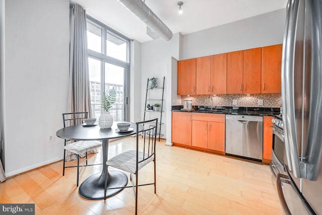 kitchen with decorative backsplash, light hardwood / wood-style floors, sink, and stainless steel appliances