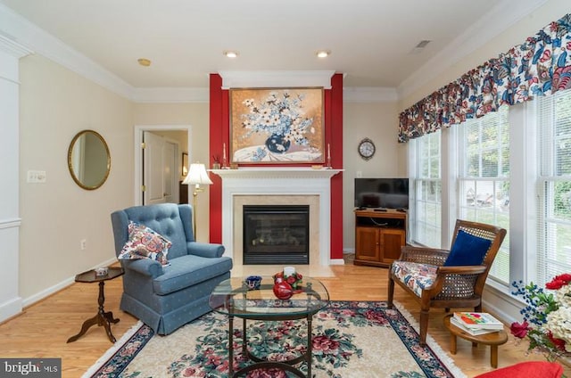 living room featuring crown molding, light hardwood / wood-style floors, and a healthy amount of sunlight