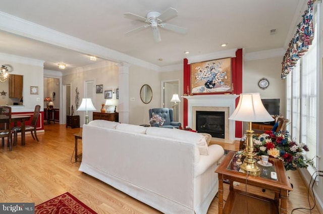 living room featuring ornate columns, crown molding, light hardwood / wood-style flooring, and ceiling fan