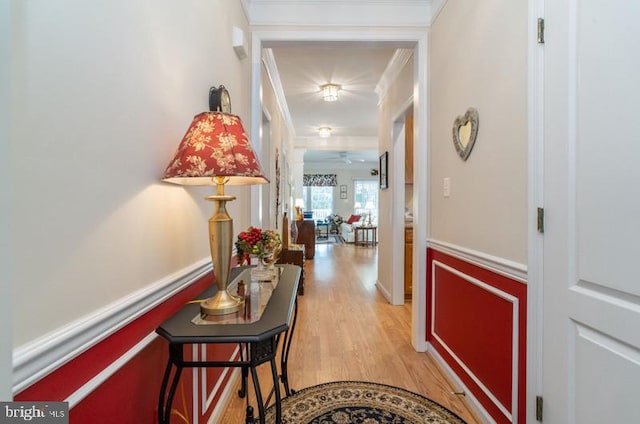 hallway with ornamental molding and light hardwood / wood-style flooring