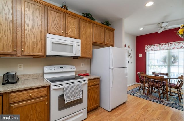 kitchen featuring light stone counters, light wood-type flooring, white appliances, and ceiling fan