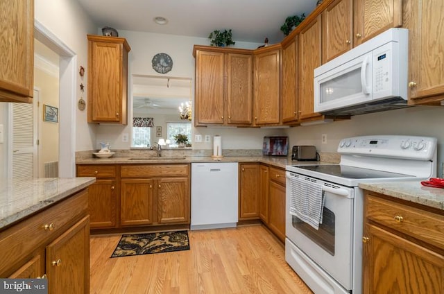 kitchen with light stone countertops, light wood-type flooring, a notable chandelier, sink, and white appliances