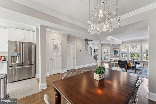 dining room featuring wood-type flooring, ornamental molding, and an inviting chandelier