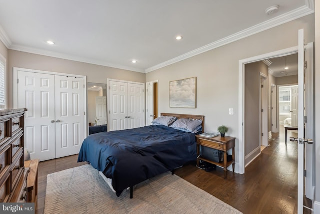 bedroom with ornamental molding, two closets, and dark wood-type flooring