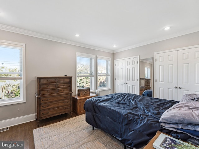 bedroom with crown molding, two closets, and dark wood-type flooring