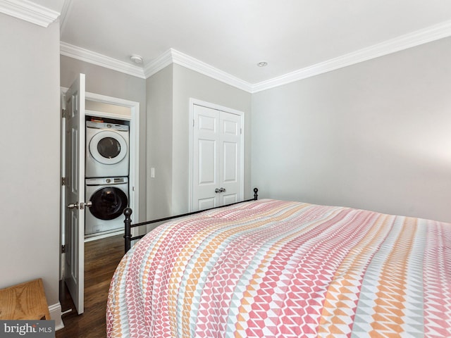 bedroom with ornamental molding, stacked washer / drying machine, dark wood-type flooring, and a closet