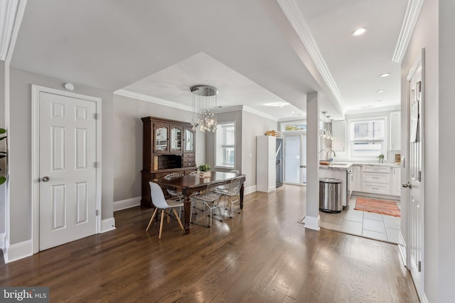 dining space featuring dark wood-type flooring, a chandelier, crown molding, and sink