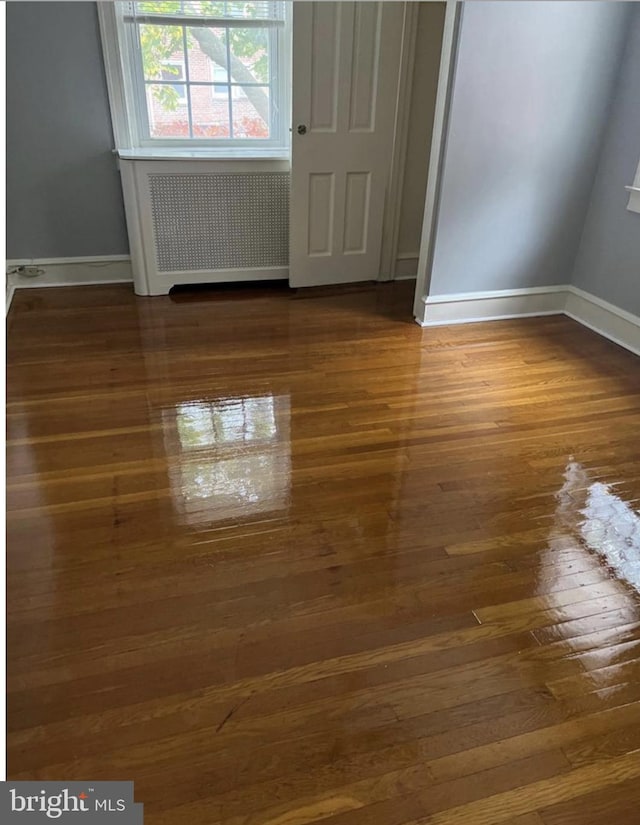 unfurnished room with dark wood-type flooring and radiator heating unit