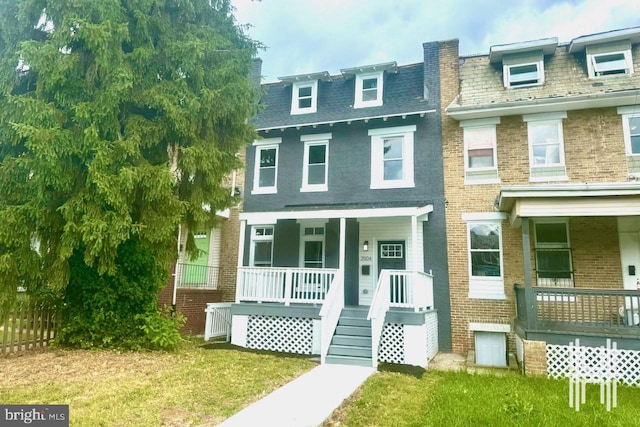 townhome / multi-family property with covered porch and a front lawn