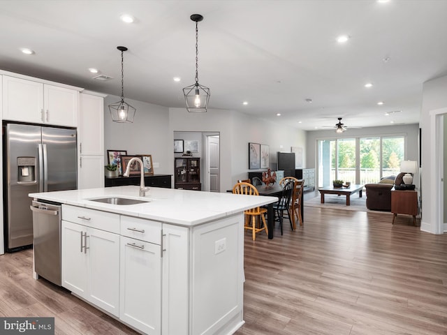 kitchen featuring an island with sink, appliances with stainless steel finishes, sink, and white cabinets