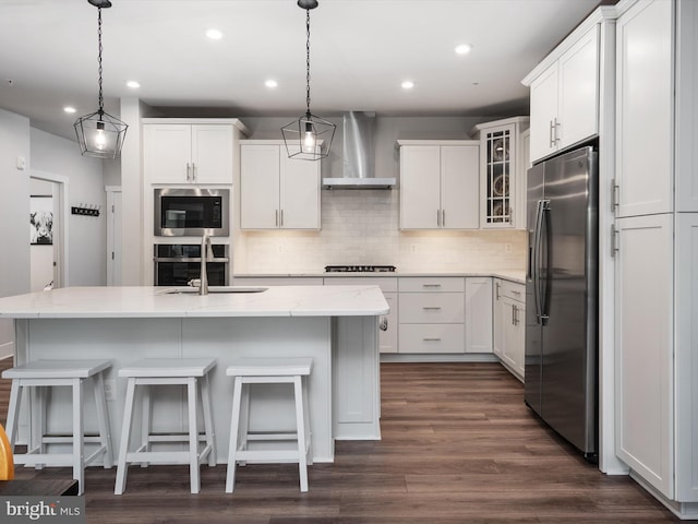 kitchen with stainless steel appliances, dark wood-type flooring, wall chimney range hood, and white cabinetry