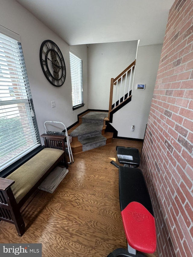 foyer featuring wood-type flooring and brick wall