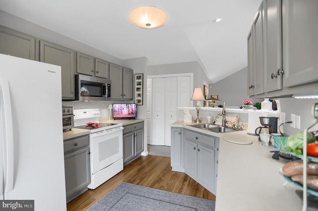 kitchen with gray cabinetry, white appliances, dark hardwood / wood-style flooring, vaulted ceiling, and sink