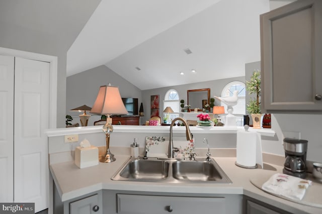 kitchen with lofted ceiling, sink, and gray cabinetry