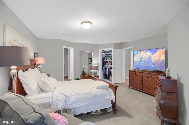 carpeted bedroom with a spacious closet and a closet