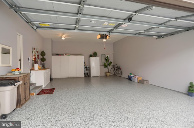 garage featuring a garage door opener, white fridge, and ceiling fan