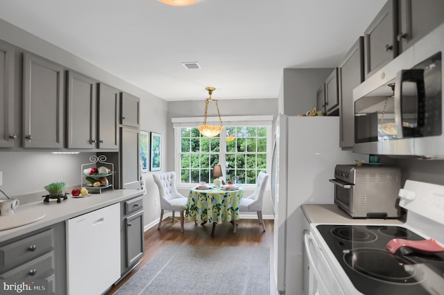 kitchen with pendant lighting, dark wood-type flooring, white appliances, and gray cabinetry