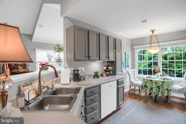 kitchen with gray cabinets, dark wood-type flooring, sink, white dishwasher, and hanging light fixtures