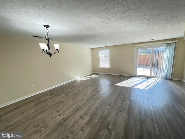 unfurnished room featuring an inviting chandelier, a textured ceiling, and dark hardwood / wood-style floors