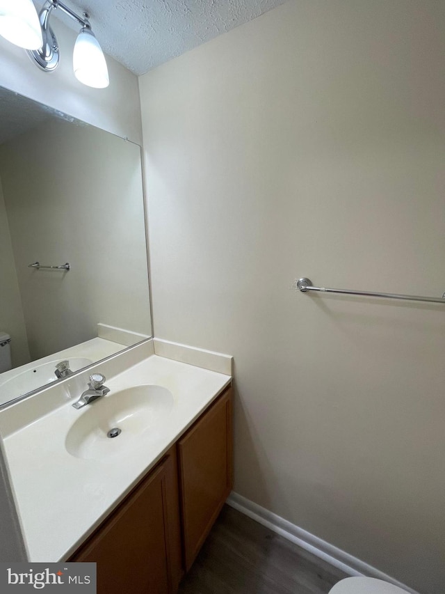 bathroom featuring vanity, toilet, a textured ceiling, and hardwood / wood-style flooring