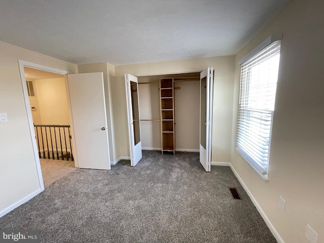 unfurnished bedroom with a textured ceiling, carpet flooring, and a closet