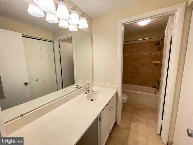 full bathroom featuring vanity, a textured ceiling, tiled shower / bath combo, tile patterned flooring, and toilet