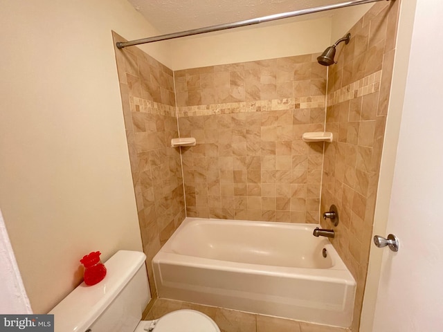 bathroom featuring tiled shower / bath combo, tile patterned flooring, and toilet