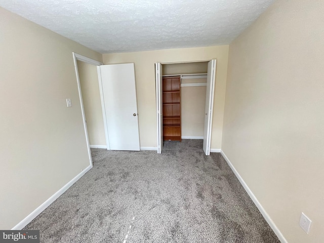 unfurnished bedroom with a textured ceiling, a closet, and carpet