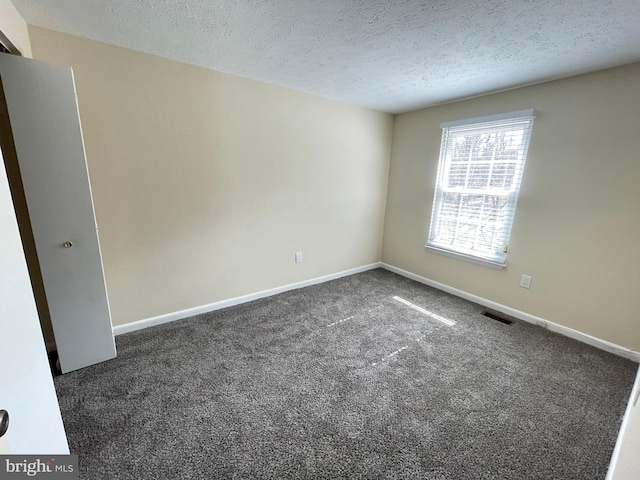 unfurnished room with dark carpet and a textured ceiling