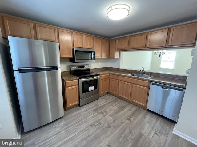 kitchen with appliances with stainless steel finishes, light hardwood / wood-style floors, and sink