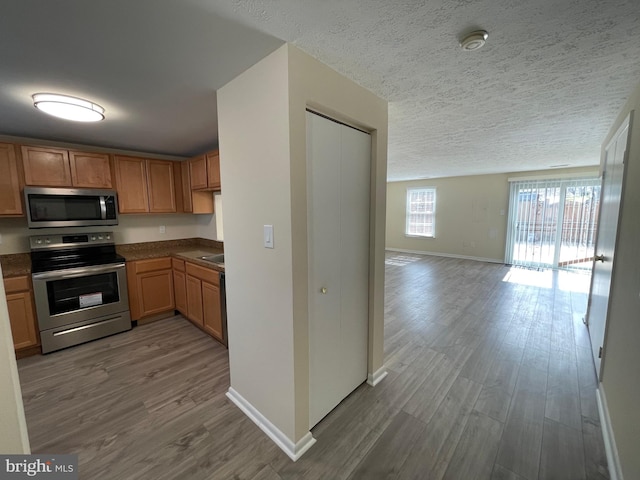 kitchen with a textured ceiling, stainless steel appliances, and hardwood / wood-style floors