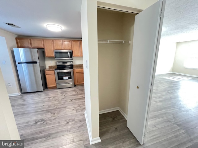 kitchen featuring stainless steel appliances and light hardwood / wood-style flooring