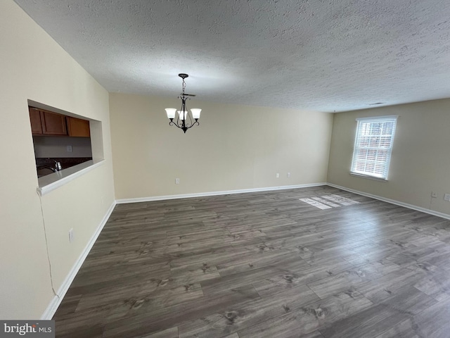 unfurnished dining area featuring a textured ceiling, dark hardwood / wood-style flooring, a chandelier, and sink