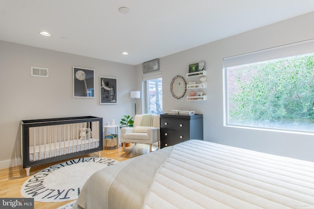 bedroom with a crib and light hardwood / wood-style flooring