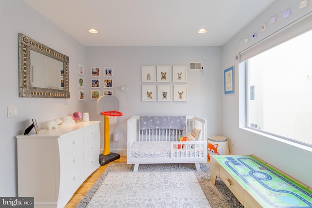 bedroom with a nursery area and light hardwood / wood-style floors