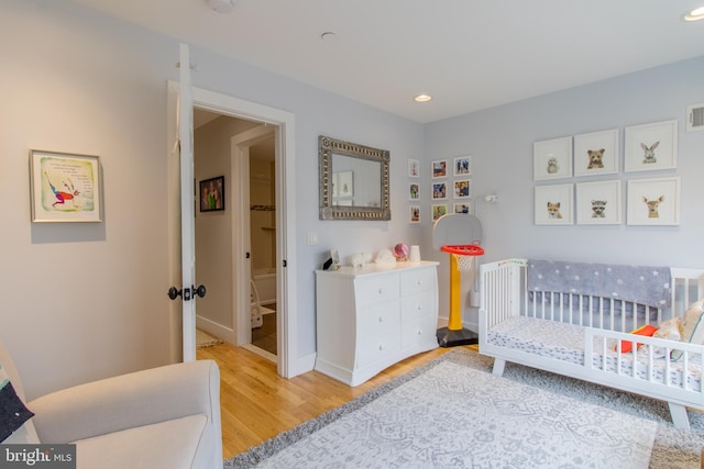 bedroom featuring light hardwood / wood-style floors and a crib