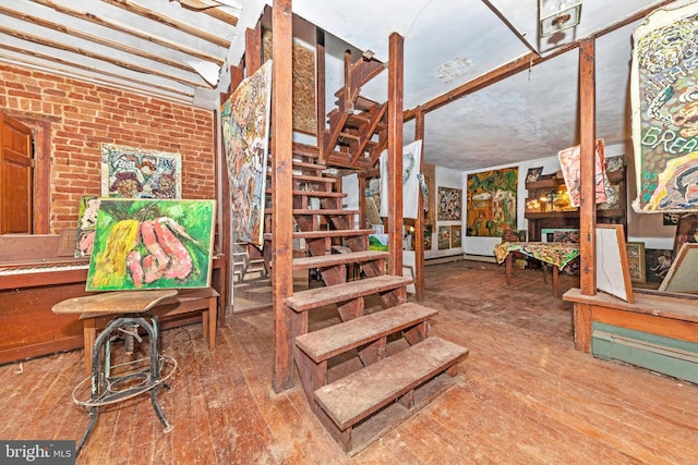 stairs featuring hardwood / wood-style flooring and brick wall