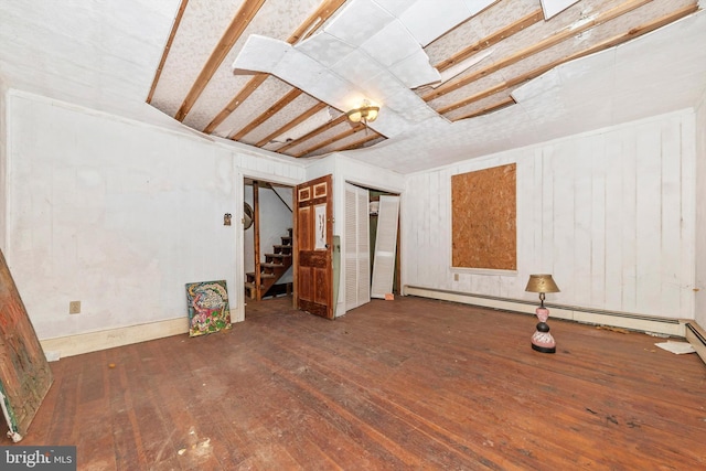 basement featuring a baseboard heating unit and dark wood-type flooring