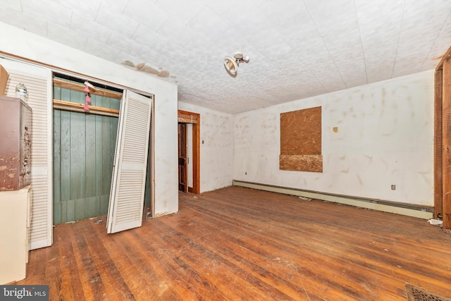 unfurnished bedroom featuring a closet, dark hardwood / wood-style floors, and a baseboard heating unit