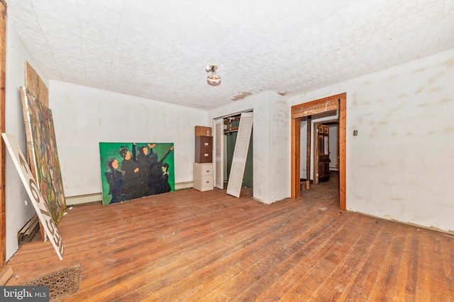 unfurnished room featuring hardwood / wood-style floors and baseboard heating